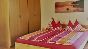 Quarto com cama de madeira, guarda-roupa grande e um quadro na parede.
