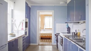 A compact kitchen with blue cabinets, a white countertop, and a small dining area visible through an open door. - Nice home in Växjö with kitchen (Växjö)