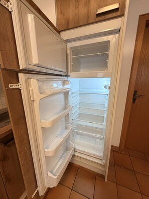 A kitchen with a built-in refrigerator, wooden cabinets, and a tiled floor. - Apartment no. 4 Amara for 1-3 pers., 42 m², 1 sep. bedroom. (Bischofswiesen)