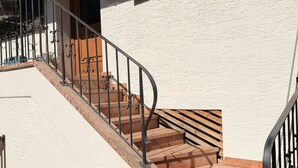 A staircase with a wooden handrail and metal balusters leading to a building with white walls and wooden doors. - Apartment no. 4 Amara for 1-3 pers., 42 m², 1 sep. bedroom. (Bischofswiesen)