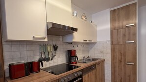 A modern kitchen with white cabinets, a wooden countertop, a red toaster, a coffee maker, and a stainless steel oven. - Apartment no. 4 Amara for 1-3 pers., 42 m², 1 sep. bedroom. (Bischofswiesen)