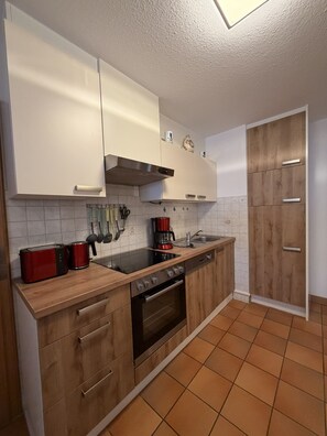A modern kitchen with white cabinets, a wooden countertop, a red toaster, a coffee maker, and a stainless steel oven. - Apartment no. 4 Amara for 1-3 pers., 42 m², 1 sep. bedroom. (Bischofswiesen)