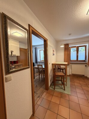 A room with a dining area, a table, chairs, a radiator, and a window with curtains. - Apartment no. 4 Amara for 1-3 pers., 42 m², 1 sep. bedroom. (Bischofswiesen)