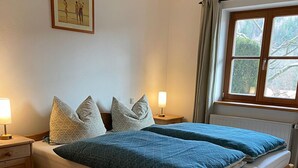 Un letto matrimoniale con struttura in legno, due comodini con lampade, un quadro appeso al muro e una finestra con tende.