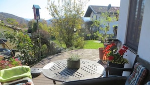 Un patio con un tavolo rotondo, sedie e piante in vaso.