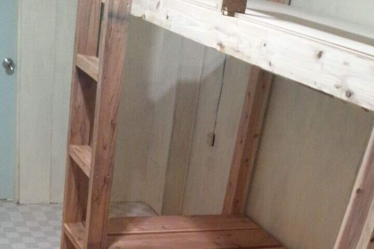 Un lit superposé en bois avec un motif à carreaux sur le sol.