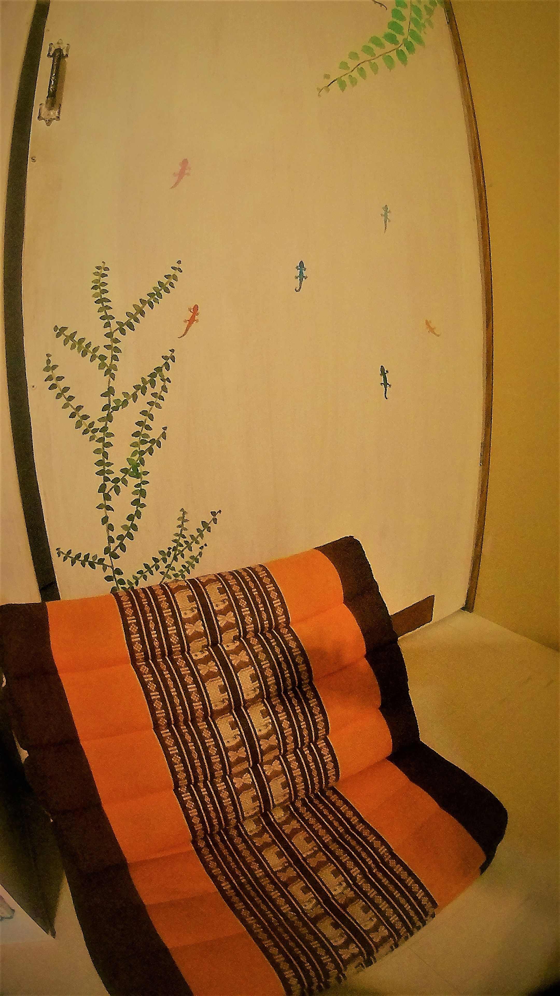 A room with a bed, a plant, and a patterned blanket.