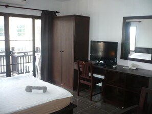 A hotel room with a bed, a desk with a computer, a chair, a wardrobe, and a balcony with a view. - Faa Apartment (Vientiane)