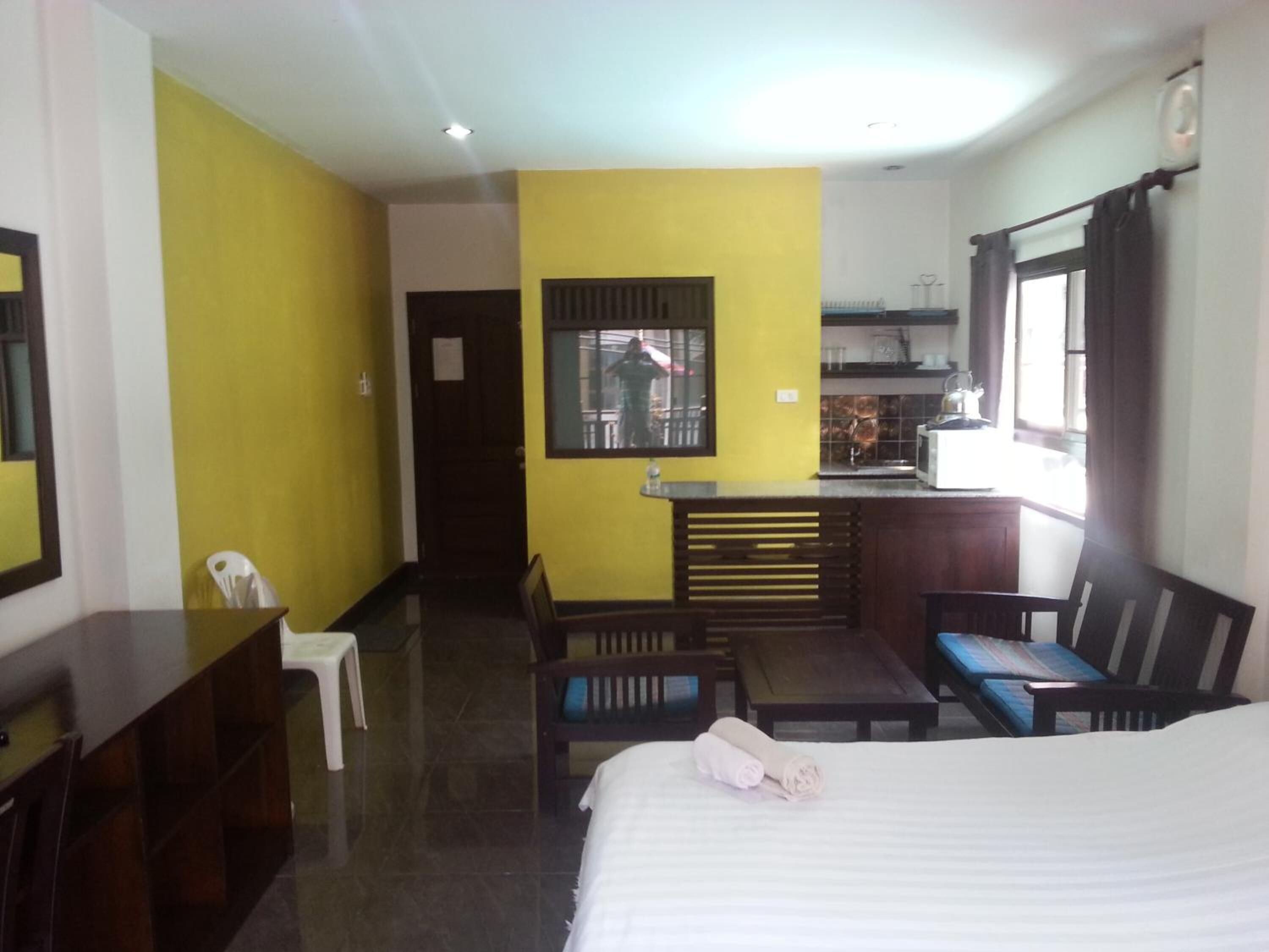 A hotel room with a bed, a desk, a chair, a small table, and a window with curtains.
