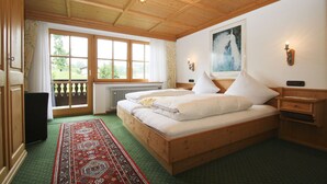 Ein Schlafzimmer mit Holzwandverkleidung, einem großen Bett, Blick ins Freie und einem Gemälde an der Wand.