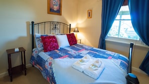 A neatly made bed with a blue and white quilt, two pillows, and a folded towel on the bed. - Rubys Cottage (Penola)