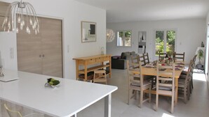 A modern kitchen with a dining area, wooden furniture, and a large window providing natural light. - Gorgeous home in Montélimar (Montélimar)