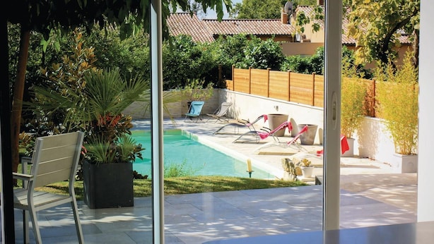 A pool area with lounge chairs, a wooden fence, and potted plants. - Gorgeous home in Montélimar (Montélimar)