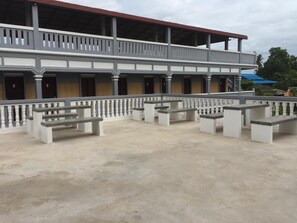 Un bâtiment doté d’un balcon couvert, de plusieurs portes et d’un espace extérieur aménagé pour s’asseoir.