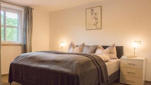Une chambre à coucher avec un lit, des tables de chevet et une fenêtre avec des rideaux.