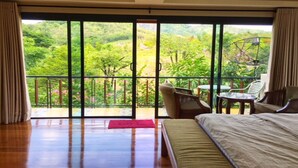 A bedroom with a large sliding glass door leading to a balcony overlooking a lush garden. - The Organery Retreat (Muak Lek)