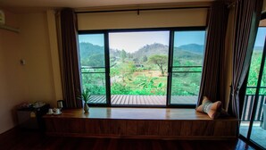 A room with a large window, a wooden bench, and a small table with a plant. - The Organery Retreat (Muak Lek)