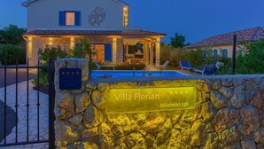 Villa Florian, ein Gebäude mit Steinmauern und einem Ziegeldach, mit Schwimmbad und Liegestühlen.