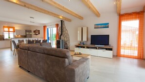 Ein modernes Wohnzimmer mit einer Couch, einem Fernseher und einer Küche im Hintergrund.