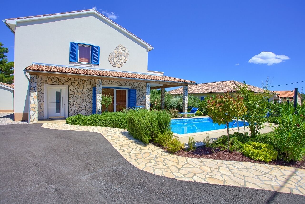 Una casa de dos pisos con fachada de piedra, piscina y un patio cubierto.