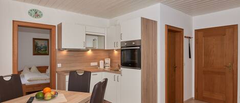 A compact kitchen with white cabinets, a built-in oven, and a coffee maker.