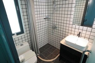 Un baño con lavamanos blanco, inodoro, ducha con puerta de cristal y espejo.