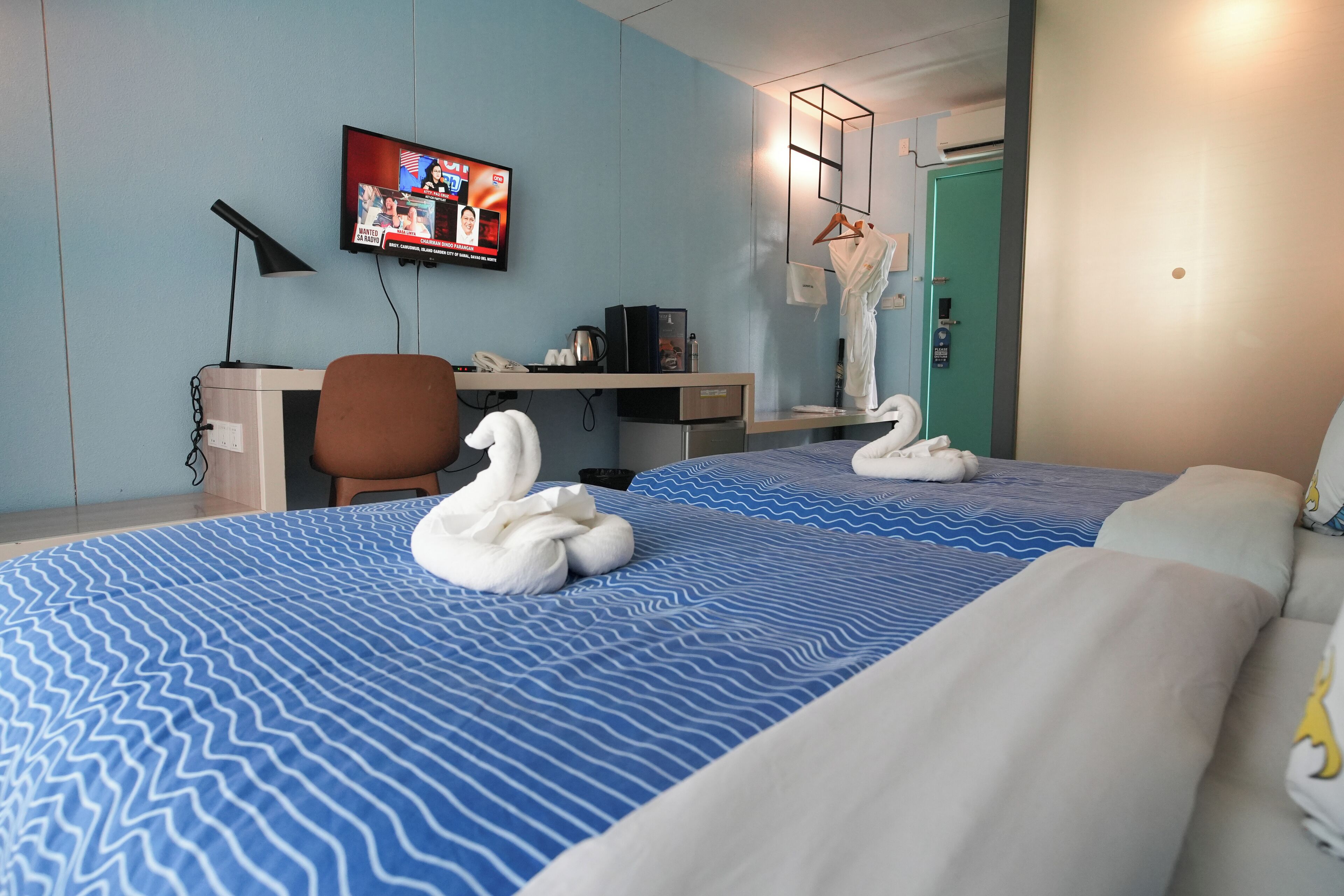 A hotel room with a bed, a desk, a television, and a mirror.