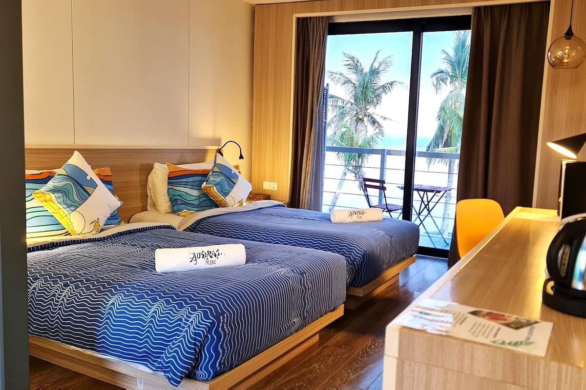 A hotel room with a bed, a desk, a chair, and a view of the beach.