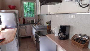 Eine kleine Küche mit Kühlschrank, Herd, Spüle und Kaffeemaschine.
