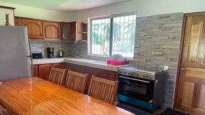 Una cocina con armarios de madera, estufa, refrigerador y una mesa de comedor con sillas.