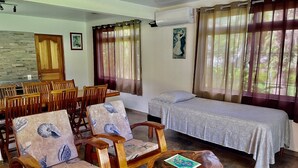 Una habitación con una cama, una mesa de comedor con sillas y un banco de madera con una revista.