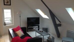 Eine moderne Loftwohnung mit einer schwarzen Couch, einem Flachbildfernseher und einem Esstisch.