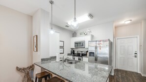 A modern kitchen with granite countertops, stainless steel appliances, and a bar area with stools.