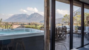 Una vasca idromassaggio su un pontile di legno con vista sulle montagne.