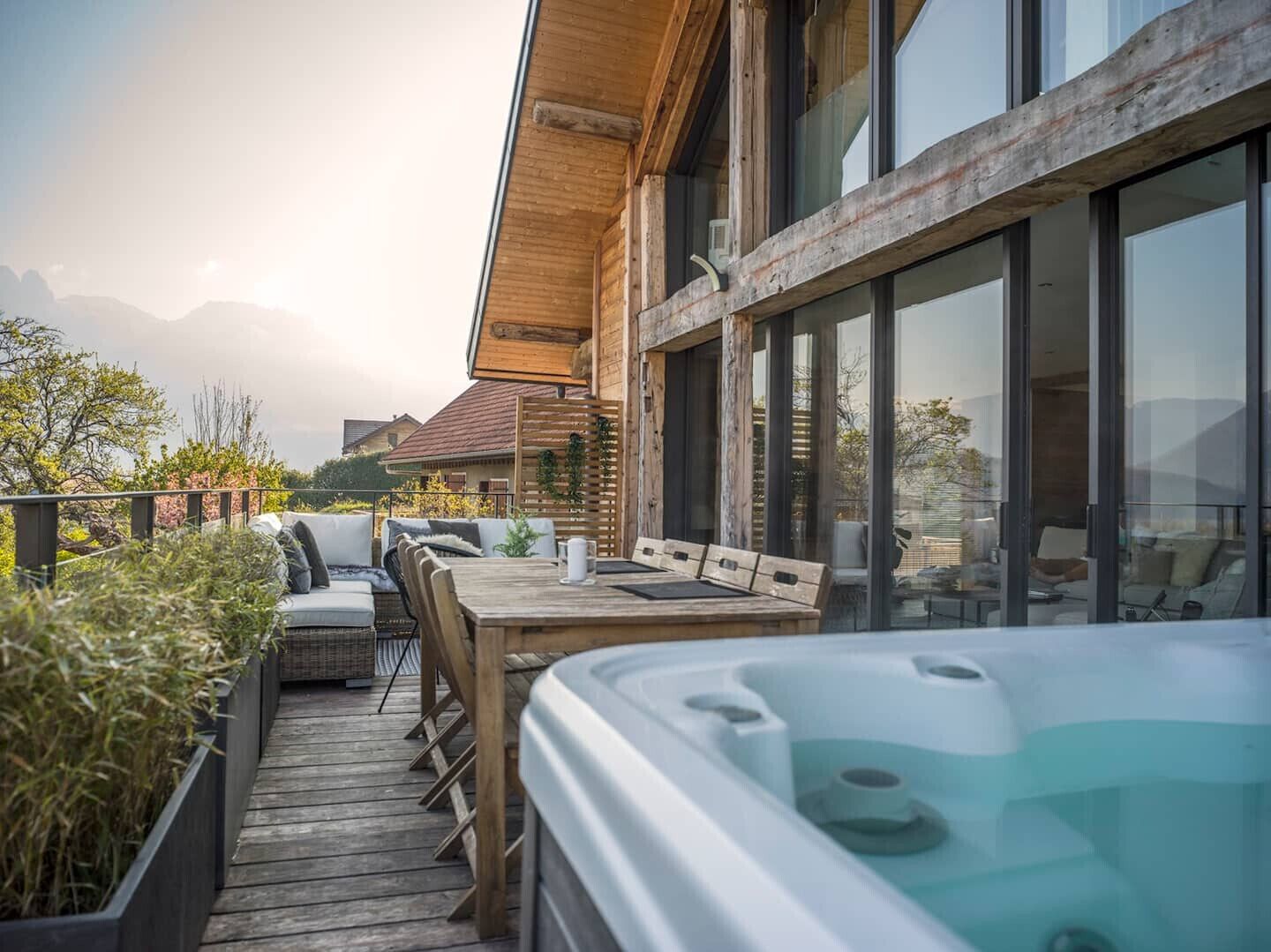 Een houten terras met buitenmeubilair en een jacuzzi.