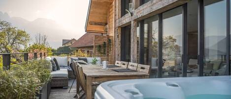 Een houten terras met buitenmeubilair en een jacuzzi.