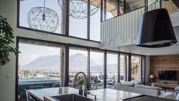 Una cucina moderna con una grande isola, un'area pranzo e un soggiorno con vista sulle montagne.