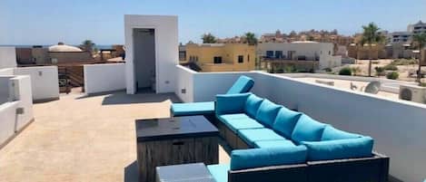 Terrassa al terrat amb un sofà blau, una taula petita i una porta que condueix a l'interior.