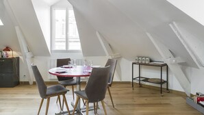 A dining area with a round table, four chairs, and a small side table with bottles. - Odorico - En centre-ville, proche gare (Rennes)