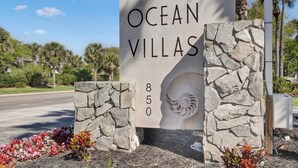 Een bord voor Ocean Villas, met een stenen muur en een spiraalvormig ontwerp.