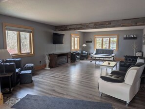 A spacious living room with a fireplace, a flat-screen TV, and a large window.