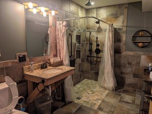 A bathroom with a shower, a sink, a toilet, and a mirror.