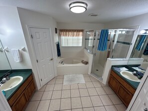 Une salle de bain avec une baignoire, une douche, deux lavabos et des toilettes.