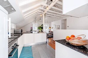 A modern kitchen with a central island, a dining area with a round table, and a living space with a sofa.
