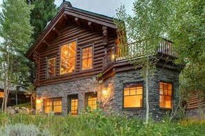 A log cabin with a stone facade, large windows, and a balcony.