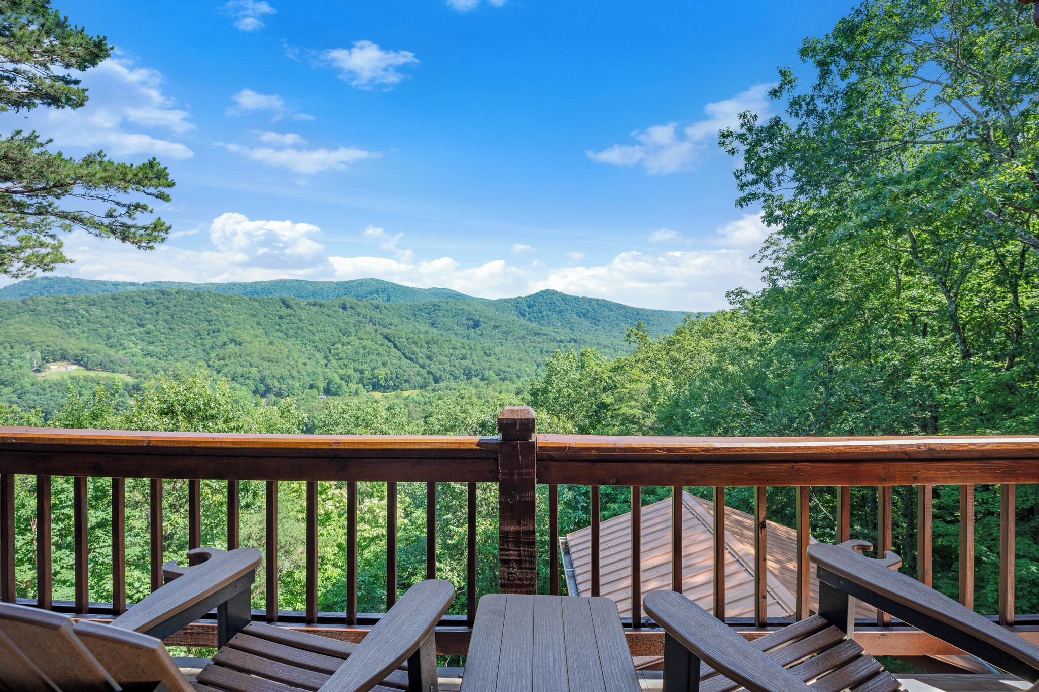 A wooden deck with a view of green mountains under a clear sky.