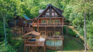 Uma cabana de madeira com vários níveis e varandas, cercada por uma floresta densa.
