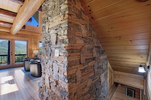 A wooden cabin interior with a stone fireplace, wooden deck, and outdoor seating.