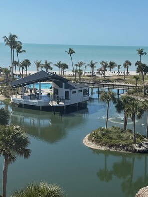Une propriété située au bord de l’eau, avec une maison sur pilotis, une piscine et une plage en arrière-plan.