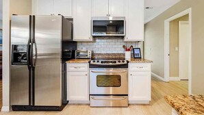 A modern kitchen with stainless steel appliances, white cabinetry, and a granite countertop. - Look Promo DEALS, Resort Like Waterfront, Orlando 4/2 Home, Private Pool, Dock (Orlando)
